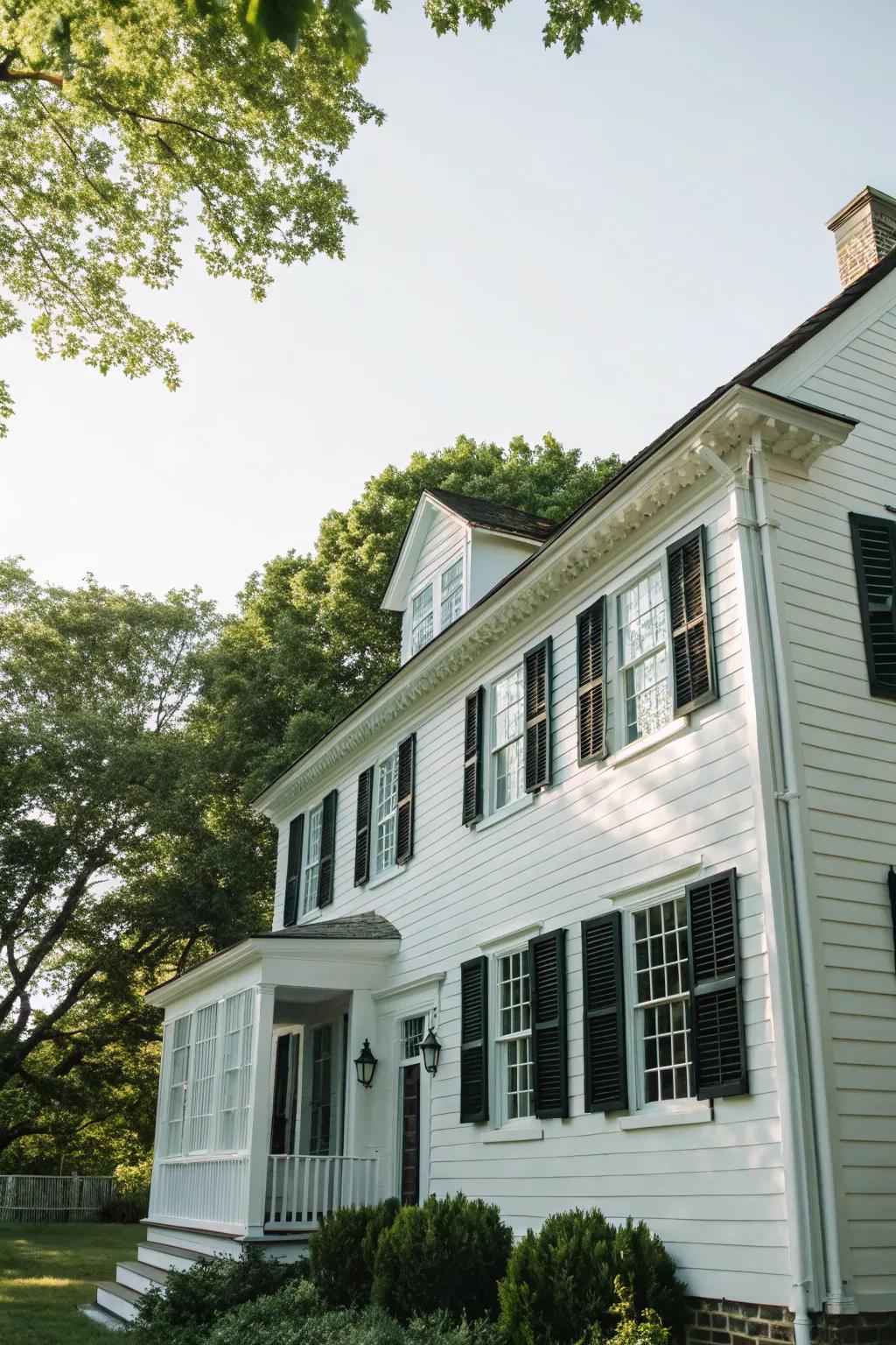A quintessential colonial residence featuring a pristine white facade with striking dark window coverings.