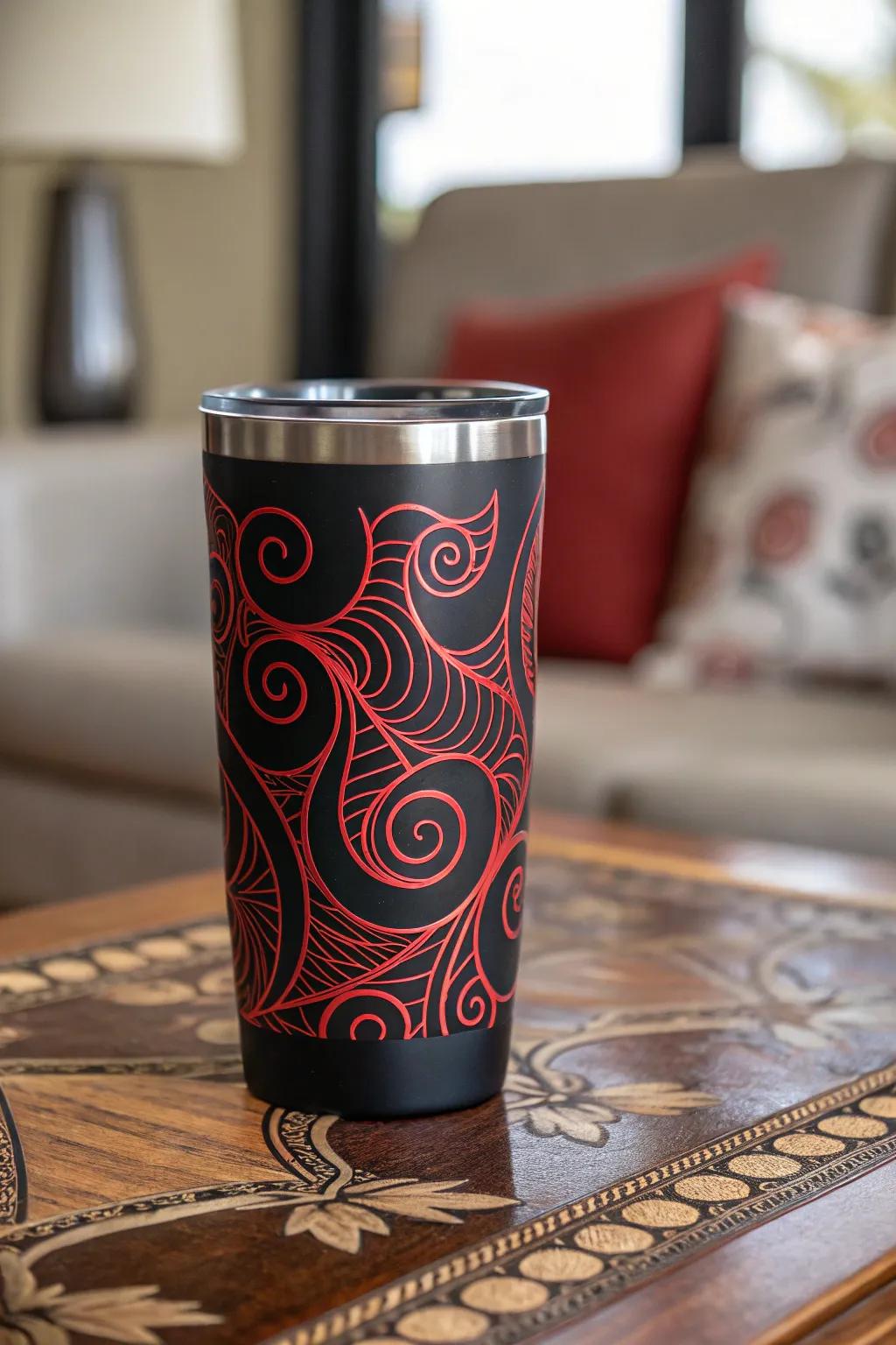 Abstract red swirls on a black tumbler create a playful appearance.