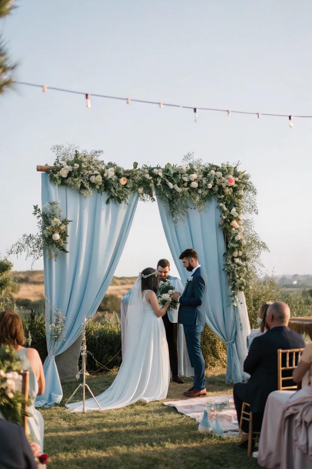 A dreamy ceremony space featuring a dusty blue backdrop that enhances the romantic ambiance.