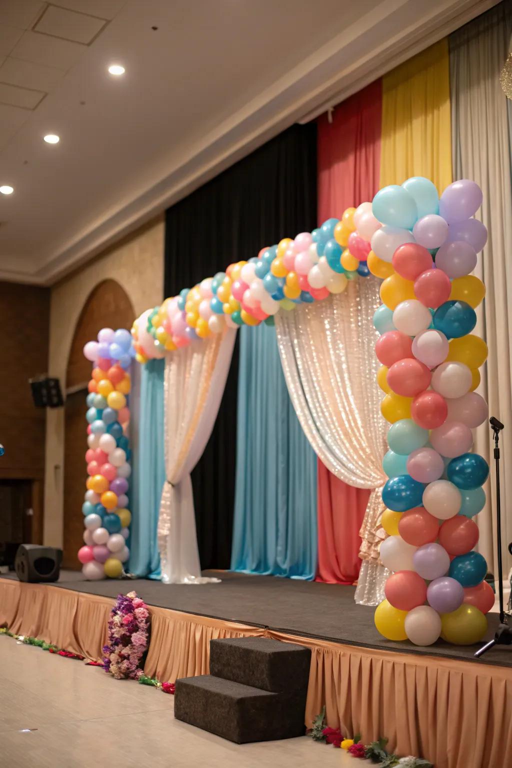 A cohesive stage design with balloons and elegant drapes.
