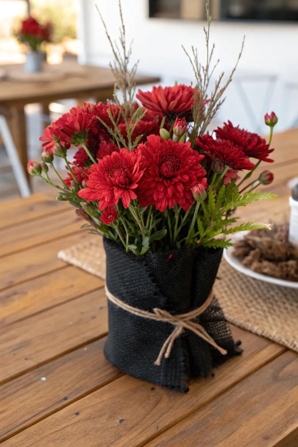 A rustic centerpiece featuring scarlet blooms wrapped in ebony burlap.