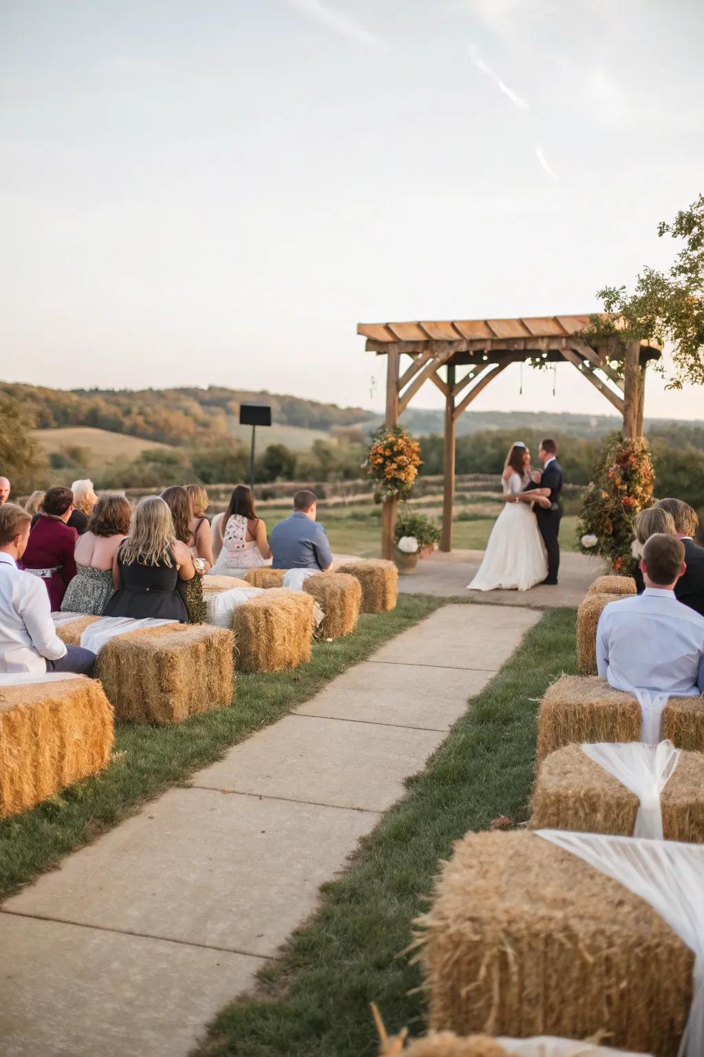 A unrefined wedding ceremony with hay bale seating draped in comfortable material.